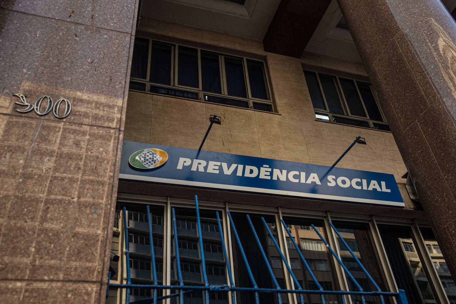 A imagem mostra a fachada de um prédio onde está localizado o órgão Previdência Social. O letreiro azul com o nome