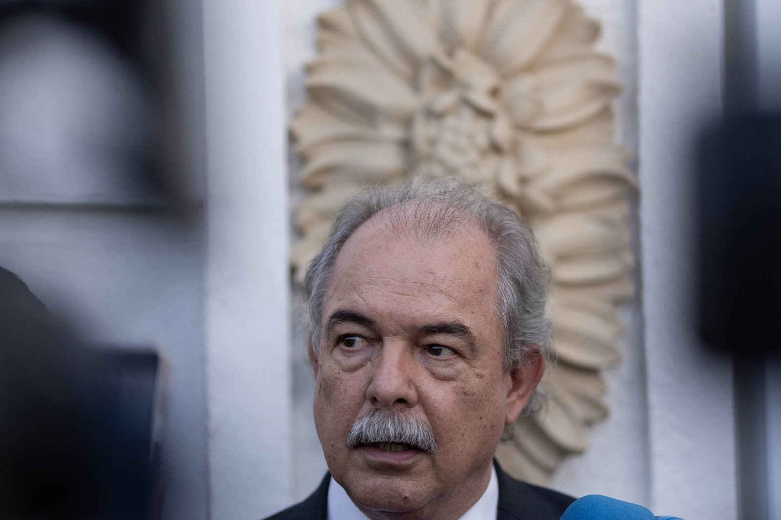 A imagem mostra o rosto do presidente do BNDES, Aloizio Mercadante. Ele é um homem com bigode e cabelos grisalhos.