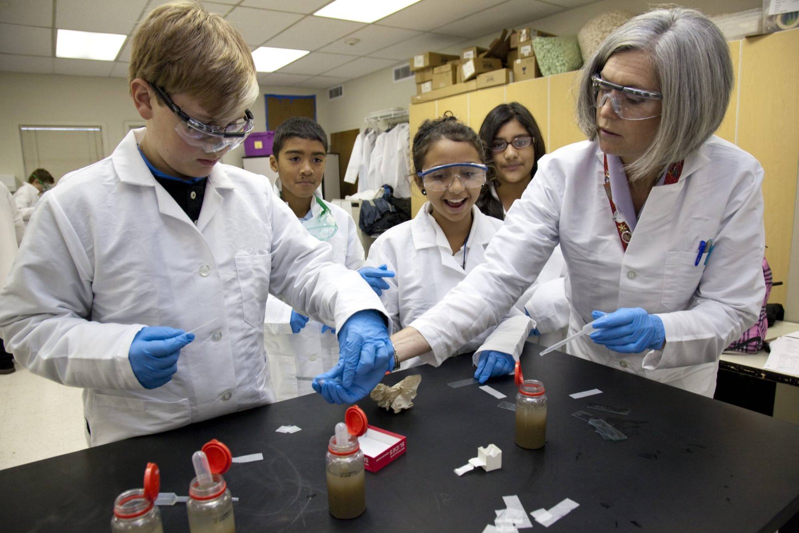 Students conduct a science experiment wearing safety gear