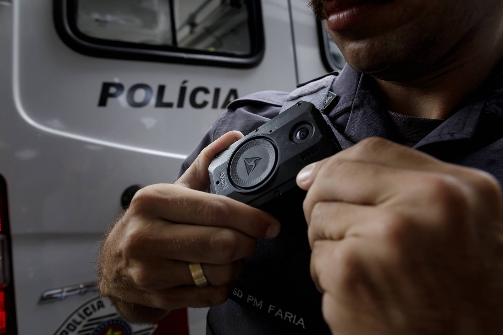 Imagem mostra policial militar segurança uma câmera corporal presa ao uniforme