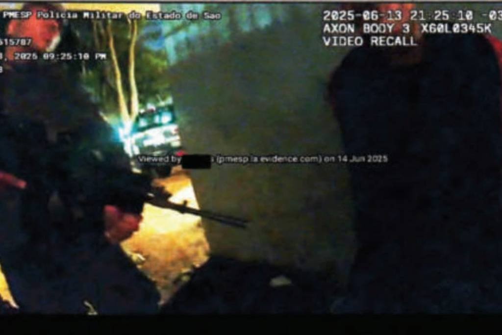 A imagem mostra uma cena de ação policial, onde um policial armado está em pé, apontando uma arma em direção a uma pessoa que está agachada ou encostada em uma parede. A iluminação é baixa, e há um veículo ao fundo. A data e hora da gravação estão visíveis no canto superior direito, indicando que foi registrada em 13 de junho de 2025.