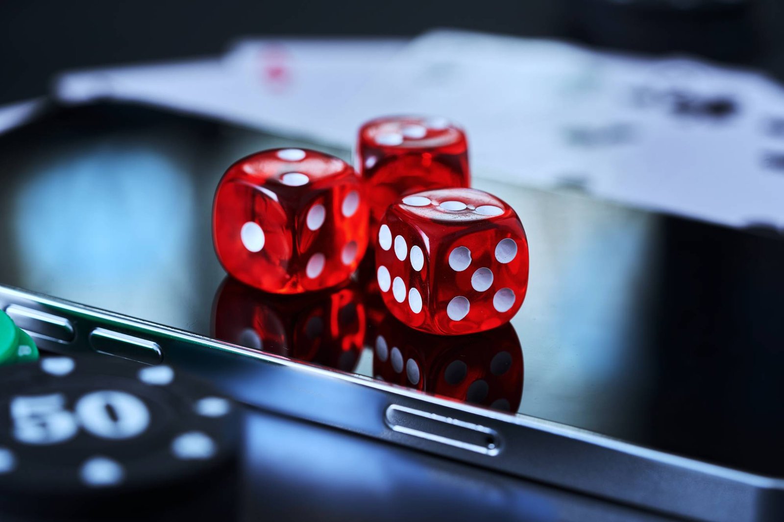 Dice resting on a smartphone alongside poker chips and playing cards