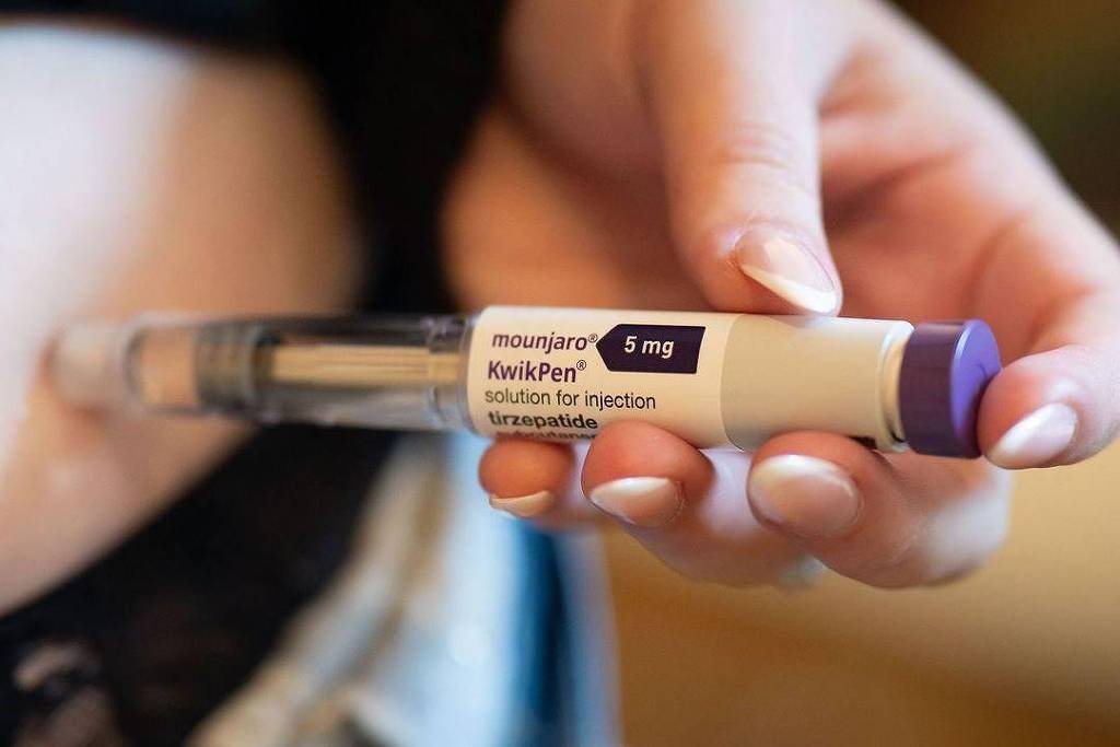 Mão segurando caneta de injeção rotulada como Mounjaro KwikPen 5 mg, solução para injeção subcutânea.
