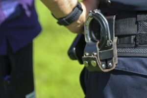 Policial com algema e arma na cintura