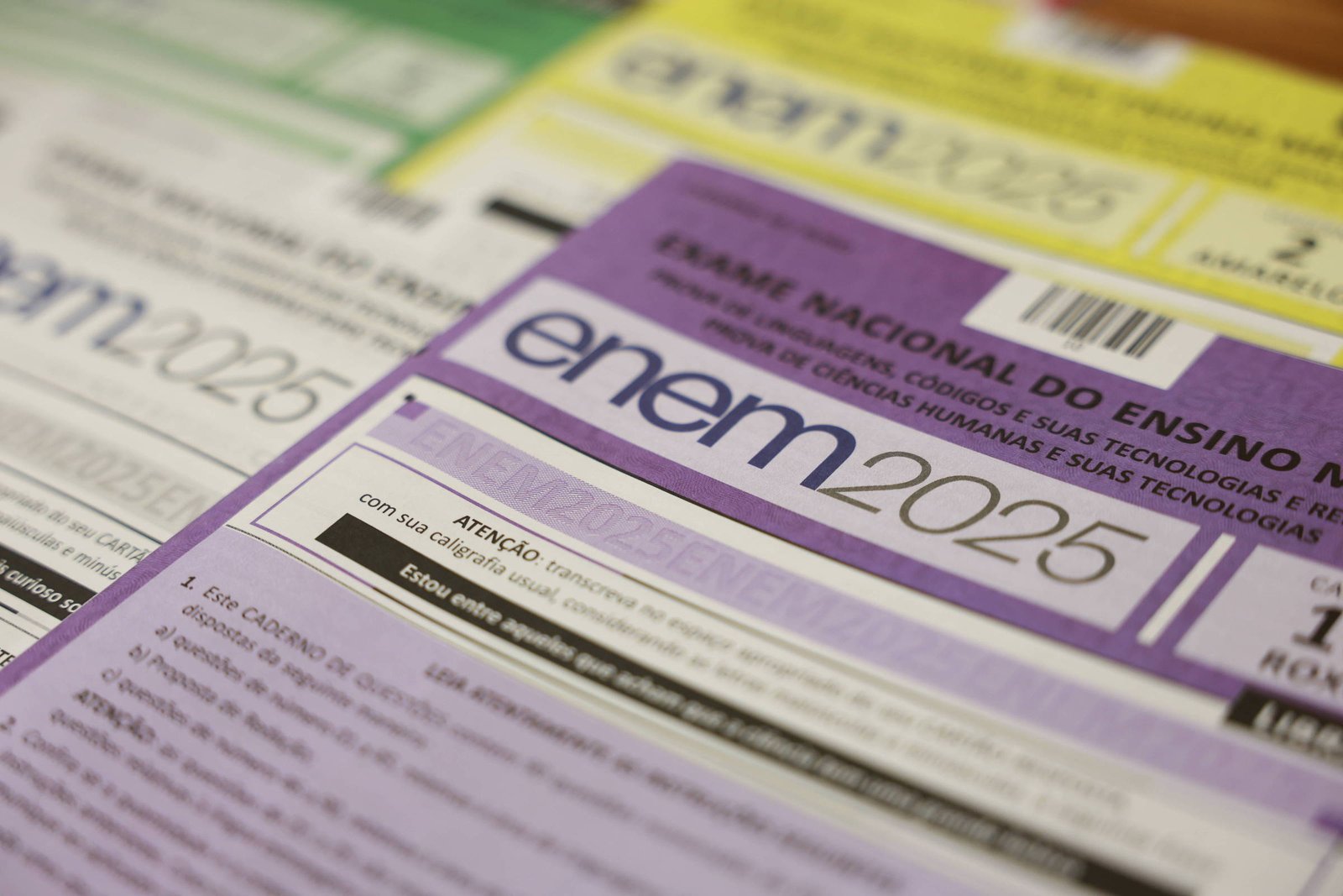 Cartões de inscrição do Exame Nacional do Ensino Médio (ENEM) 2025 dispostos em sequência, com destaque para o cartão roxo em primeiro plano. Cada cartão exibe o logo