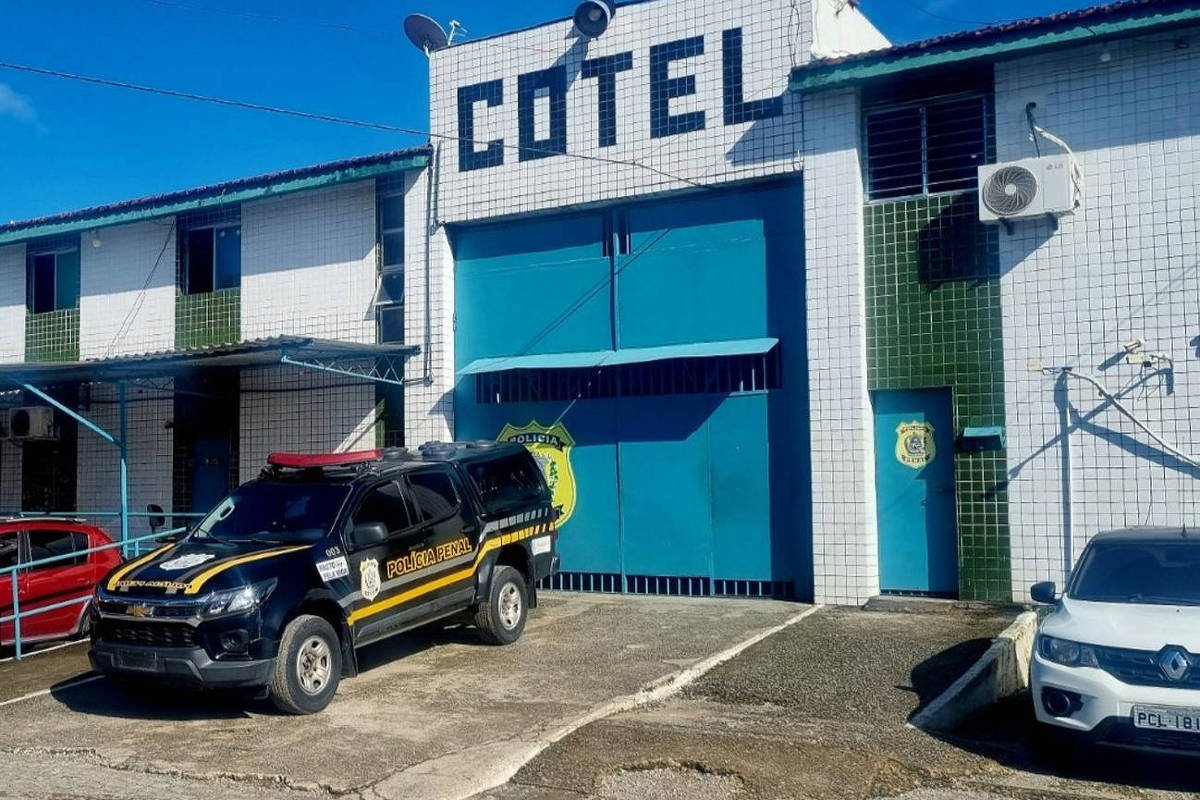 Fachada de prédio branco com detalhes verdes e azuis, com a palavra